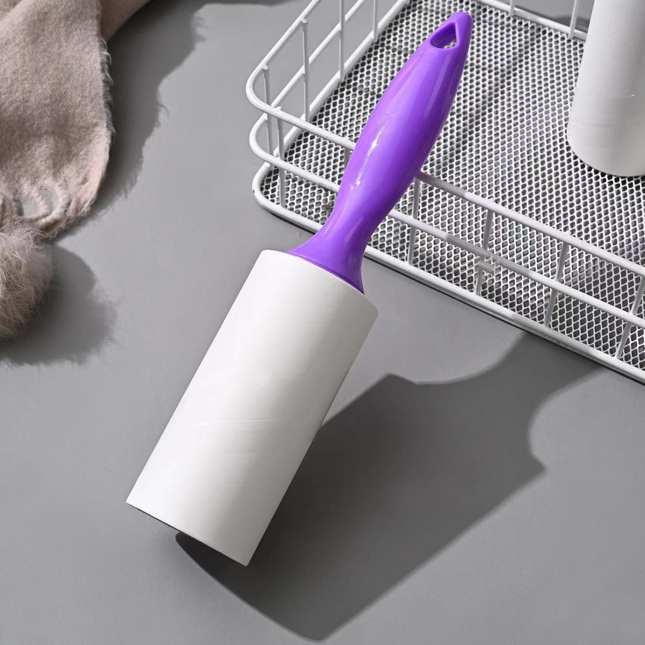 Tearable Lint Remover with purple handle on a gray surface, ideal for removing lint and pet hair.