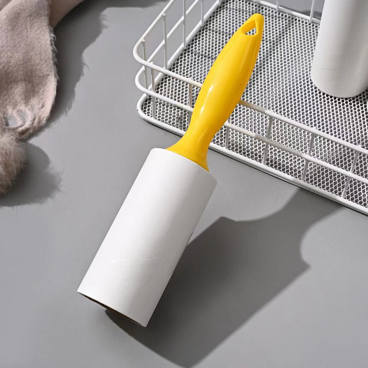 Tearable Lint Remover with yellow handle on a gray surface, ideal for cleaning lint and pet hair.